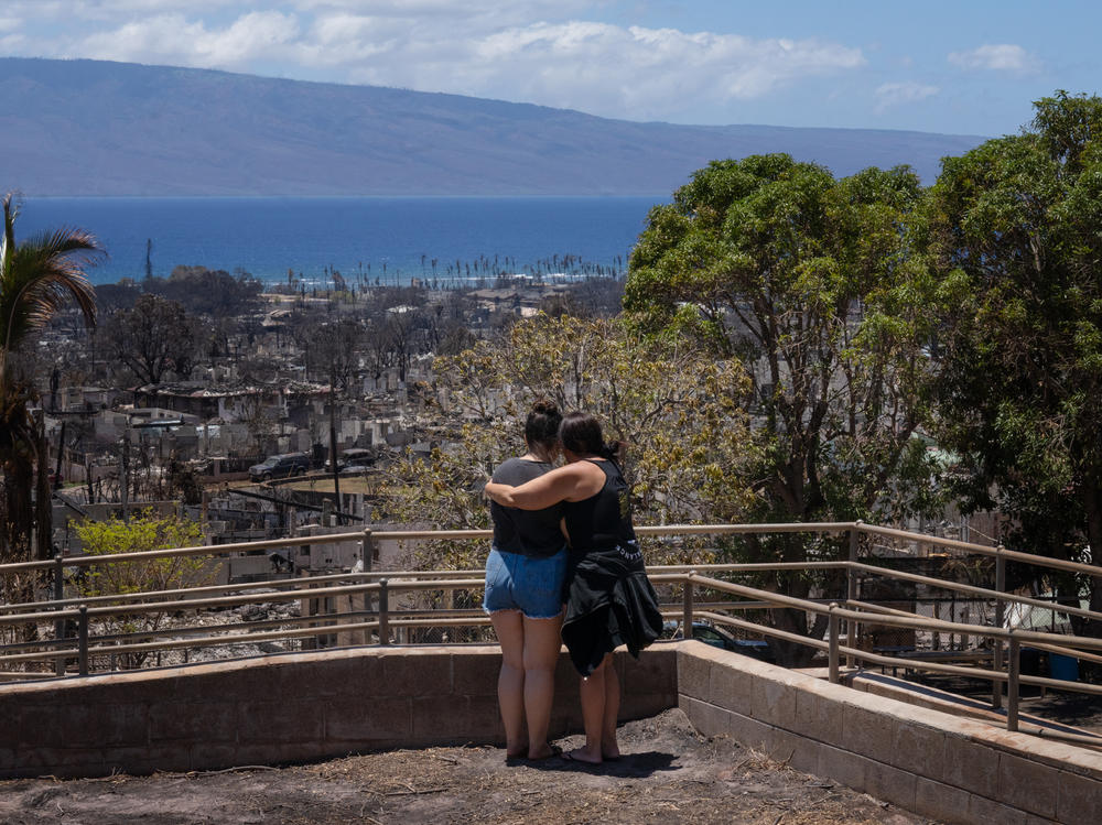 Two women embrace and cry as they look out over a burned area in Lahaina, Hawaii in August 2023. A new survey finds most Americans expect the impacts of climate change to worsen in the next 30 years, as climate scientists warn.