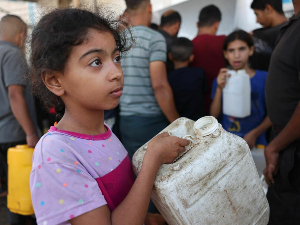 A Palestinian girl holds a container as she waits to collect potable water, in Khan Yunis, in the southern Gaza Strip, on Thursday, as battles continue between Israel and the Palestinian group Hamas.