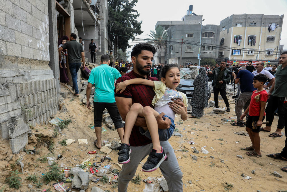 Palestinians walk near the destroyed house belonging to the Al-Maghari family on Sunday after an Israeli airstrike on Rafah, in the Gaza Strip.