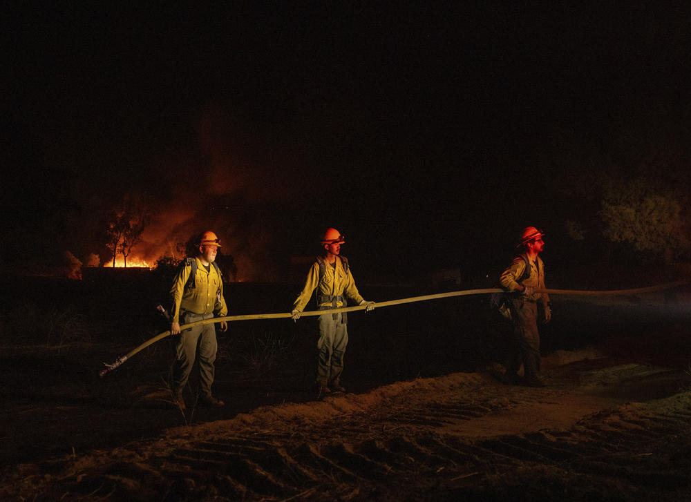 Firefighters hold hose line while battling the Highland Fire in Aguanga on Monday.
