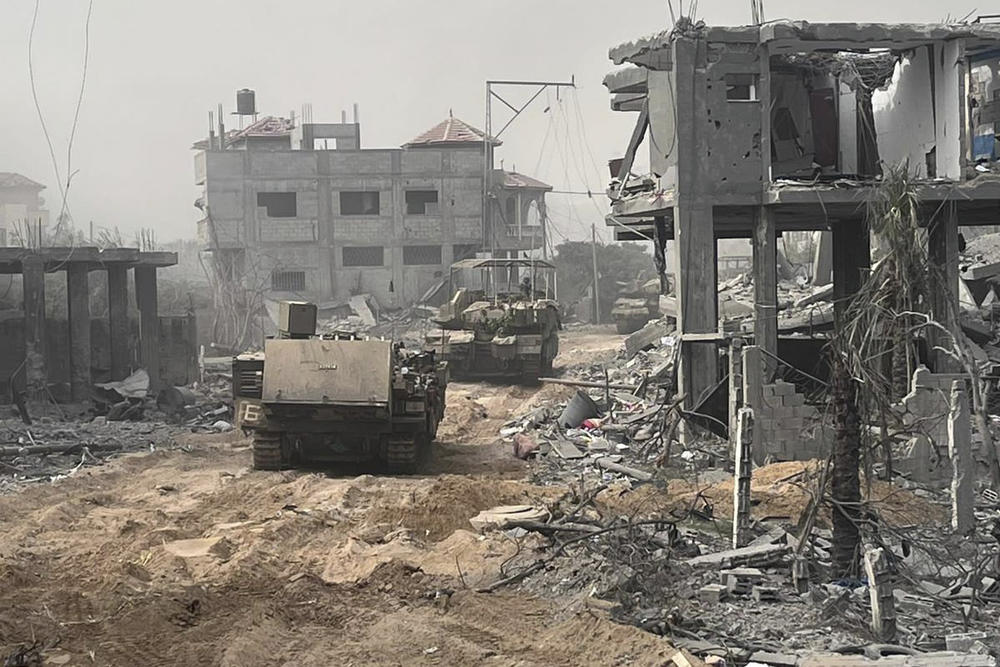Israeli armored vehicles move past destroyed buildings during the ground operation in the Gaza Strip. Experts say that Israel is unlikely to commit enough troops to fully secure Gaza City.