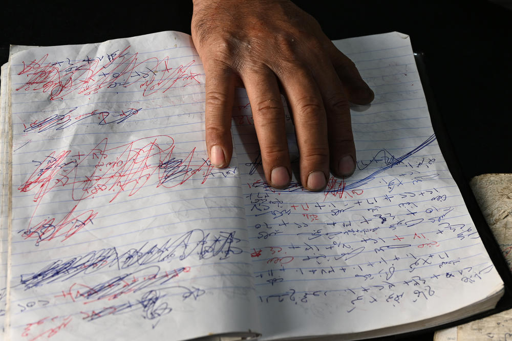 A shop owner in Ein Erik, in the occupied West Bank, shows his ledger of credit given to construction workers who cannot pay as long as travel is on hold.