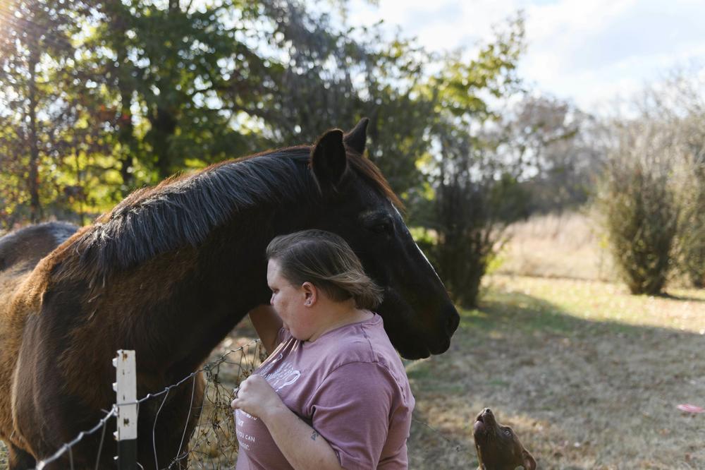 Becky Queen greets one of her horses outside her home.