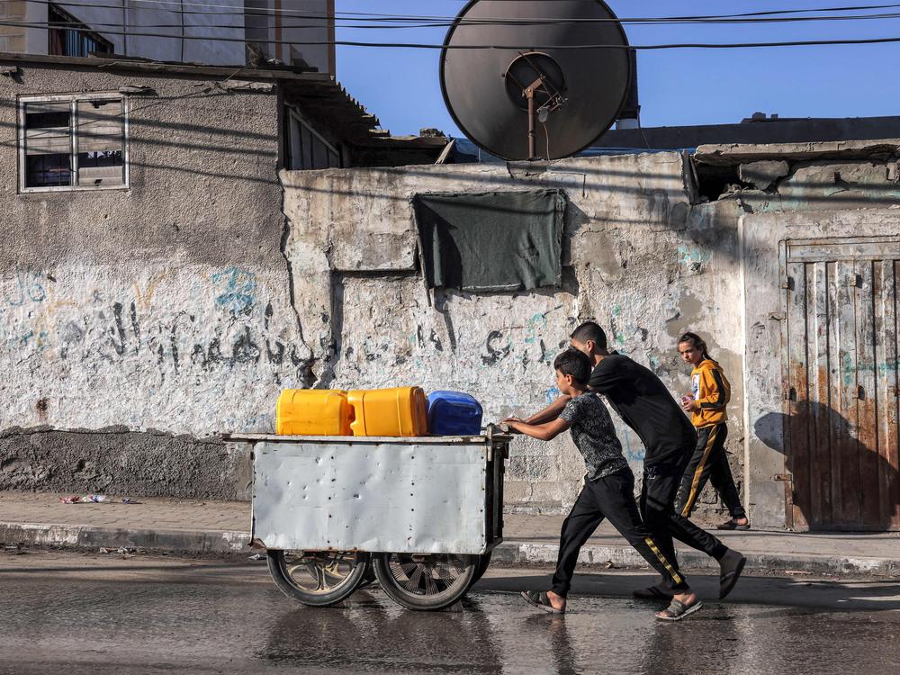 Youths push a cart loaded with jerrycans to be filled with in the southern Gaza Strip on Oct. 31. A lack of drinking water is leading to a rise in waterborne diseases, according to health officials.