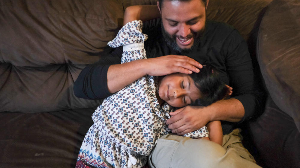 Jose Grajeda and his daughter, Victoria, cuddle before bedtime in Alpine, Tex. When Grajeda was a kid, he remembers how his parents employed a soothing caress to send him to sleep. Now he uses it with his kids. 