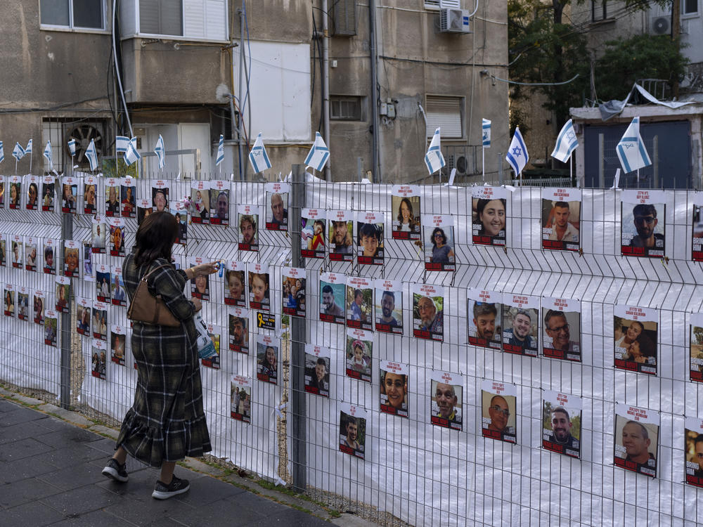 A woman looks at photographs of hostages, mostly Israeli civilians, who were abducted during the Oct. 7, unprecedented Hamas attack on Israel, in Ramat Gan, Israel, on Wednesday.