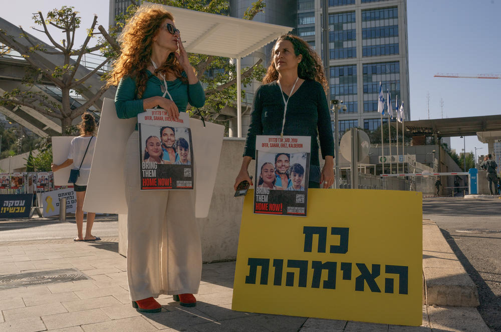 Hadas Calderon, right, who's children and ex-husband are being held hostage in Gaza holds a sign that reads 'the power of mothers' outside Israel main army base in Tel Aviv, Israel.