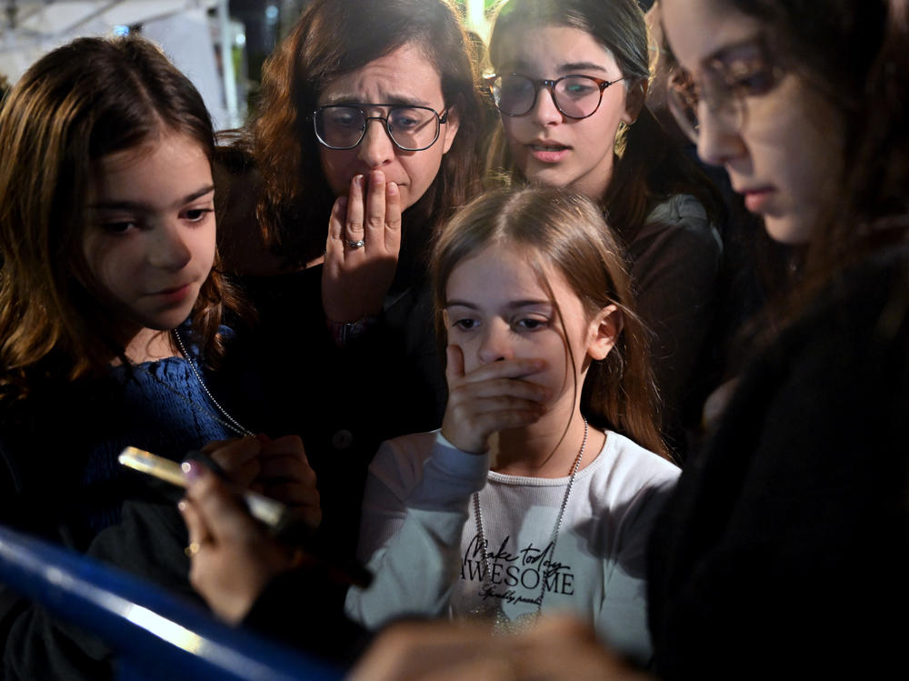 A mother and her children react to the news that Hanna Katzir, who the Palestine Islamic Jihad claimed died in captivity, is among the 13 Israelis released. They are watching the news on their phone outside the Museum of Tel Aviv on Friday.