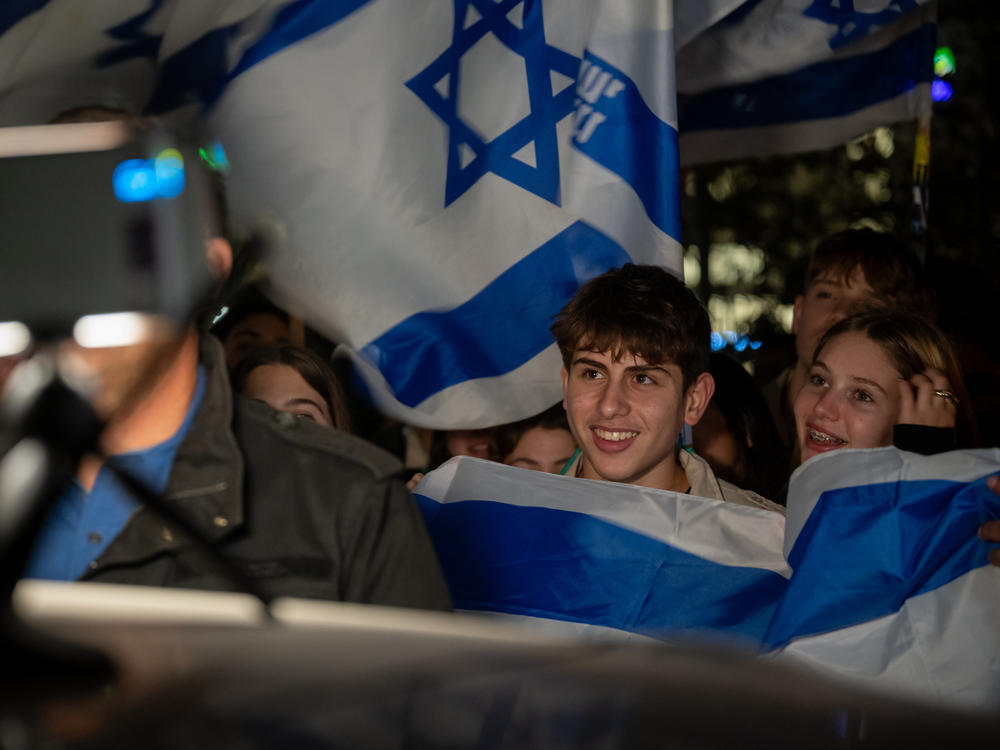 Israeli youth groups wave Israeli flags as a helicopter with hostages released earlier by Hamas lands at Schneider medical center on Sunday.