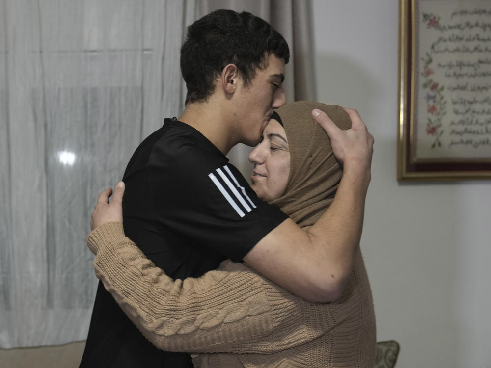 Released Palestinian prisoner Muhammad Abu Al-Humus, 17, hugs his mother after arriving home in the east Jerusalem neighborhood of Issawiya, early Tuesday. Eleven Israelis were also released in the latest Israel-Hamas swap of captives.