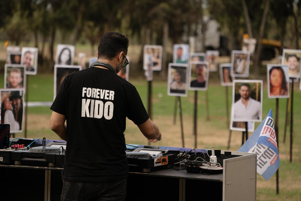 A DJ plays music among hundreds of photos showing people taken captive or killed by Hamas militants on Oct. 7.