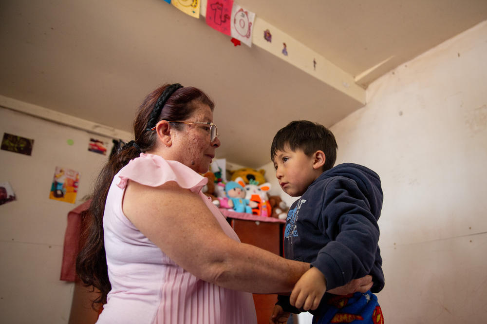 Salamanca ayuda a su nieto menor, Matías López, de 4 años, a vestirse. Vive en un hogar multigeneracional con sus hijos y siete de sus ocho nietos en San Cristóbal.