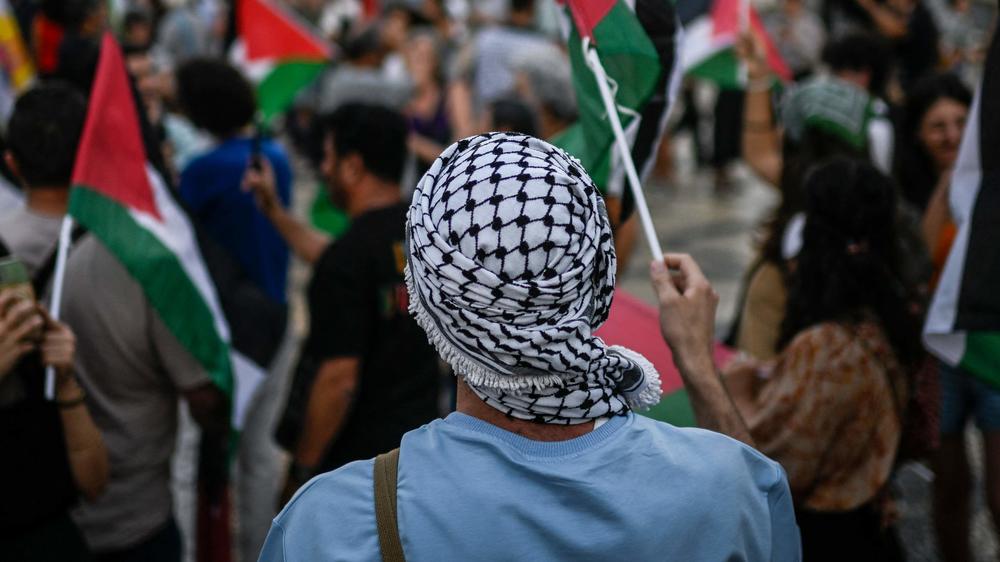 A protestor wearing a keffiyeh waves a Palestinian flag during a rally in support of Palestinians in Lisbon in October.