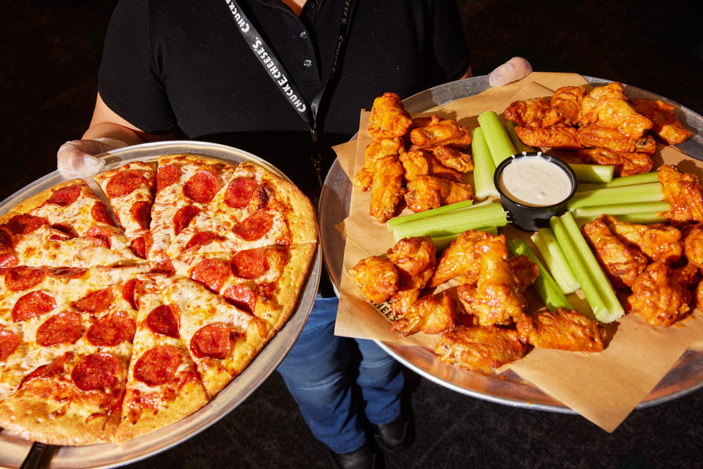 A cast member brings pizza and chicken wings to guests at the Northridge location.