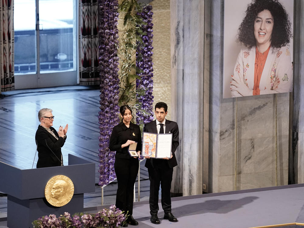 Nobel Committee chair Berit Reiss-Andersen (L) applauds as Kiana Rahmani and Ali Rahmani pose with the award on behalf of their mother during the 2023 Nobel Peace Prize ceremony at the Oslo City Hall on December 10, 2023.