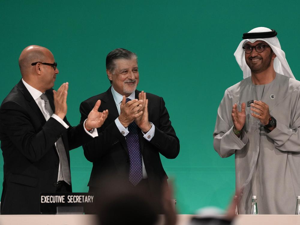Sultan al-Jaber of the United Arab Emirates, right, celebrates the end of the COP28 climate meeting with United Nations Climate Chief Simon Stiell, left, and COP28 CEO Adnan Amin on Dec. 13, 2023, in Dubai. The final deal included a modest reference to transitioning away from fossil fuels, which scientists say is crucial to avoid catastrophic warming.