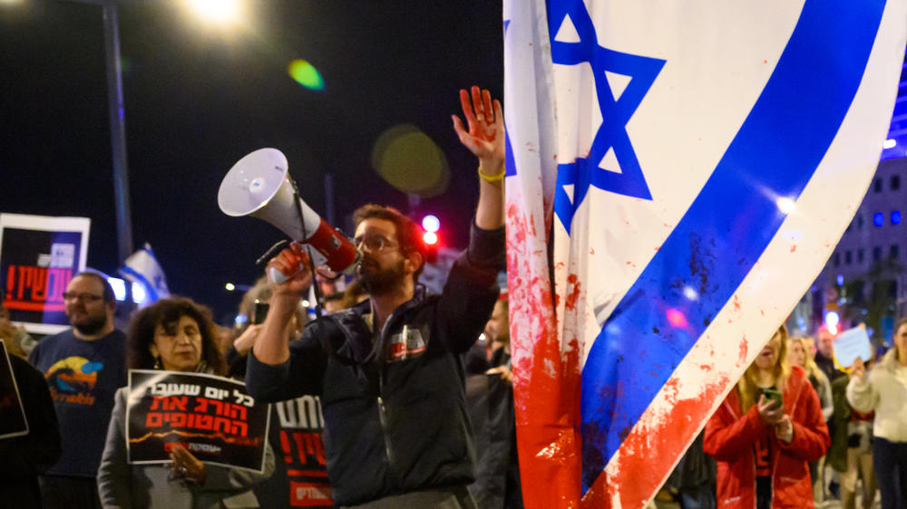 A protester with red paint on his hand marches through the streets after demonstrating outside the Israel Defense Forces headquarters on Friday in Tel Aviv, Israel. Earlier, the IDF had said its forces accidentally killed three hostages being held in Gaza when it mistakenly identified them as potential threats.