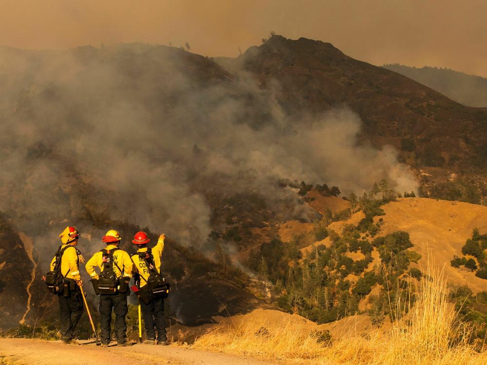 Firefighters survey the fire during operations to battle the Kincade Fire in Healdsburg, Calif., on Oct. 26, 2019.