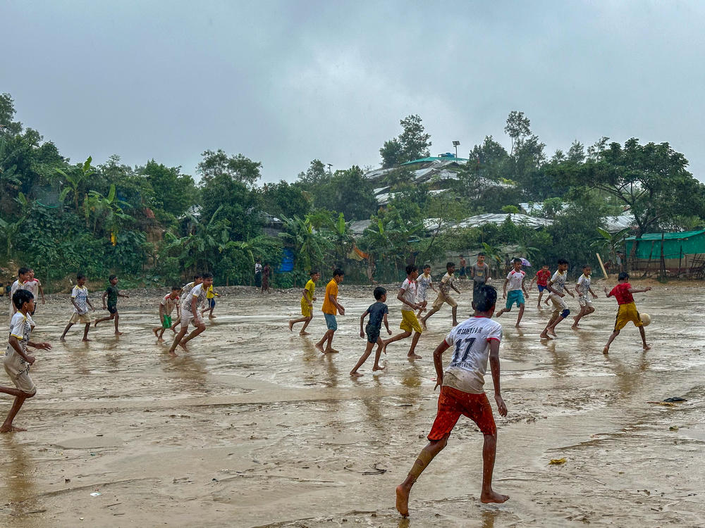 Rohingya refugee children play soccer in a December rain.