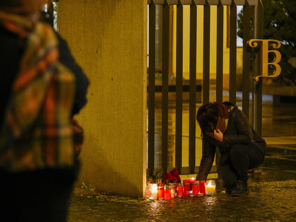 A person lights candles outside the building of Philosophical Faculty of Charles University in downtown Prague, Czech Republic, Thursday, Dec. 21, 2023.
