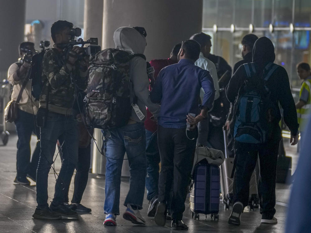 Journalists try to interview Indian passengers, who arrived in an unmarked Legend Airlines A340 from Vatry Airport in France, at the Chhatrapati Shivaji Maharaj International Airport in Mumbai, India, Tuesday, Dec. 26, 2023.