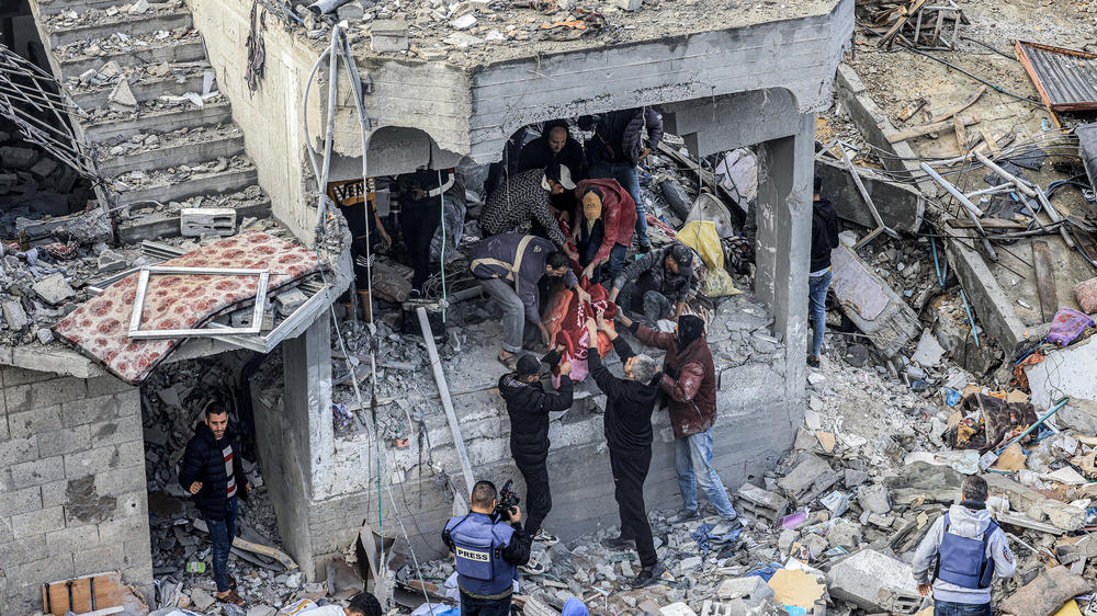 Men recover the body of a Palestinian killed in the aftermath of an overnight Israeli strike at al-Maghazi refugee camp in Gaza on Monday, as the war between Israel and Hamas carries on.