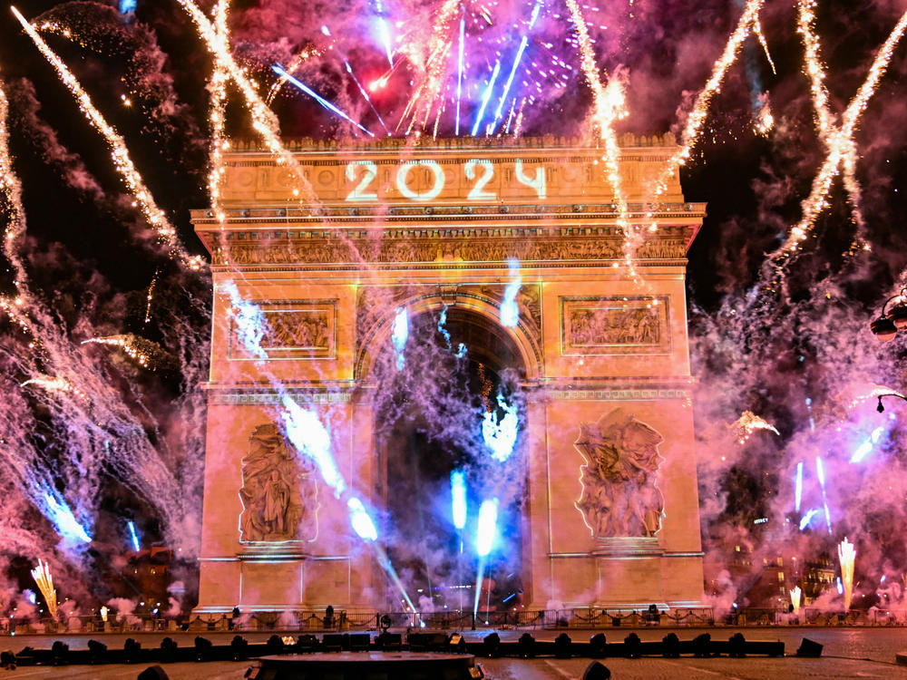Fireworks explode next to the Arc de Triomphe with 