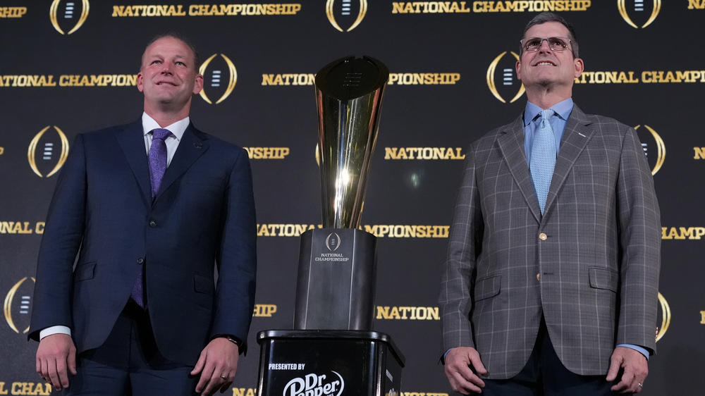 Washington head coach Kalen DeBoer, left, and Michigan head coach Jim Harbaugh pose with the trophy after a news conference ahead of the national championship NCAA College Football Playoff game between Washington and Michigan on Sunday, Jan. 7, 2024, in Houston. The game will be played Monday.