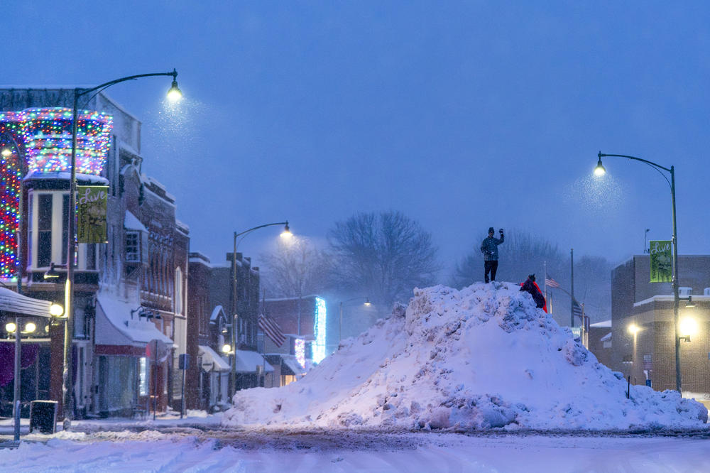 People stand on an large snow pile in Oskaloosa, Iowa, Tuesday, Jan. 9, 2024.