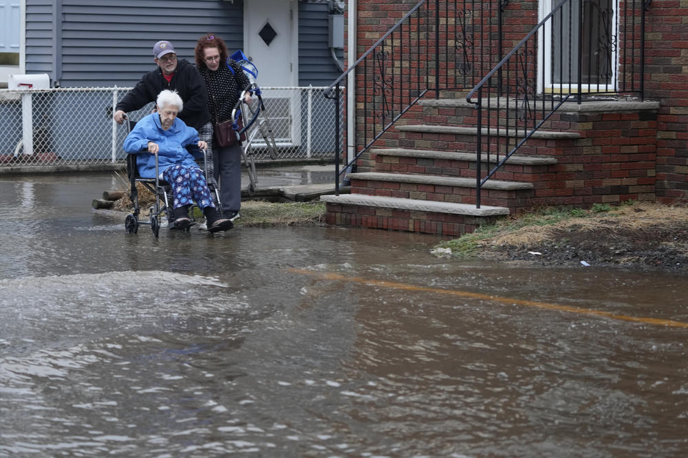 People help a woman in wheelchair through a flooded street in Lodi, N.J. on Wednesday.