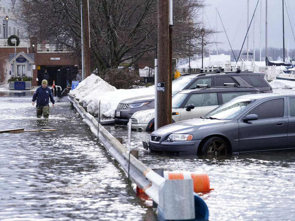 A man wades through a flooded parking lot near Widgery Wharf on Wednesday in Portland, Maine.