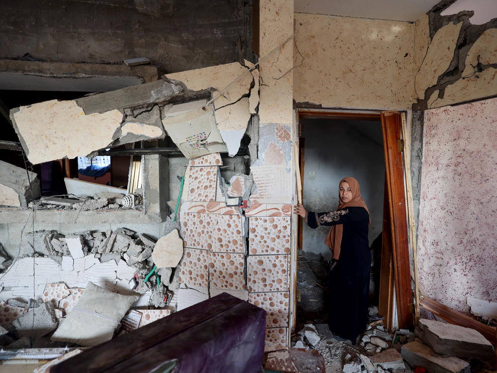 A woman stands in her damaged house in Rafah, in the southern Gaza Strip, on Friday, following Israeli bombardment amid continuing battles between Israel and the Palestinian militant group Hamas.