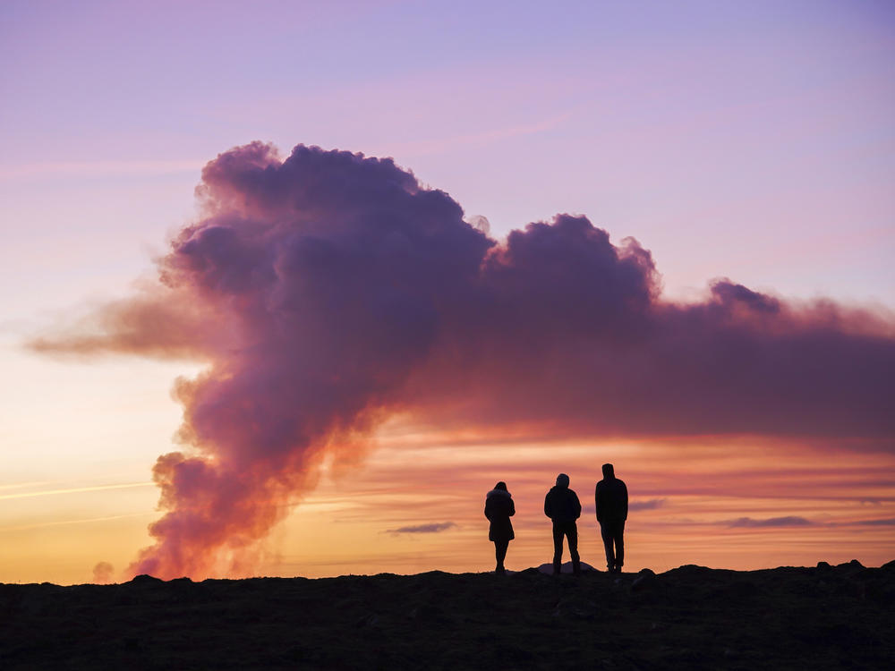 People watch from the north as the volcano erupts near Grindavík, Iceland, on Sunday.