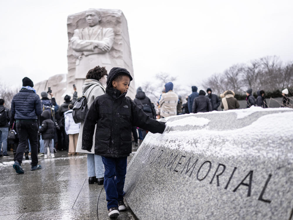 A boy plays with snow at the Martin Luther King Jr. Memorial, after the start of a wreath-laying ceremony honoring the legacy of the late civil rights leader in Washington, D.C. on Monday's holiday.