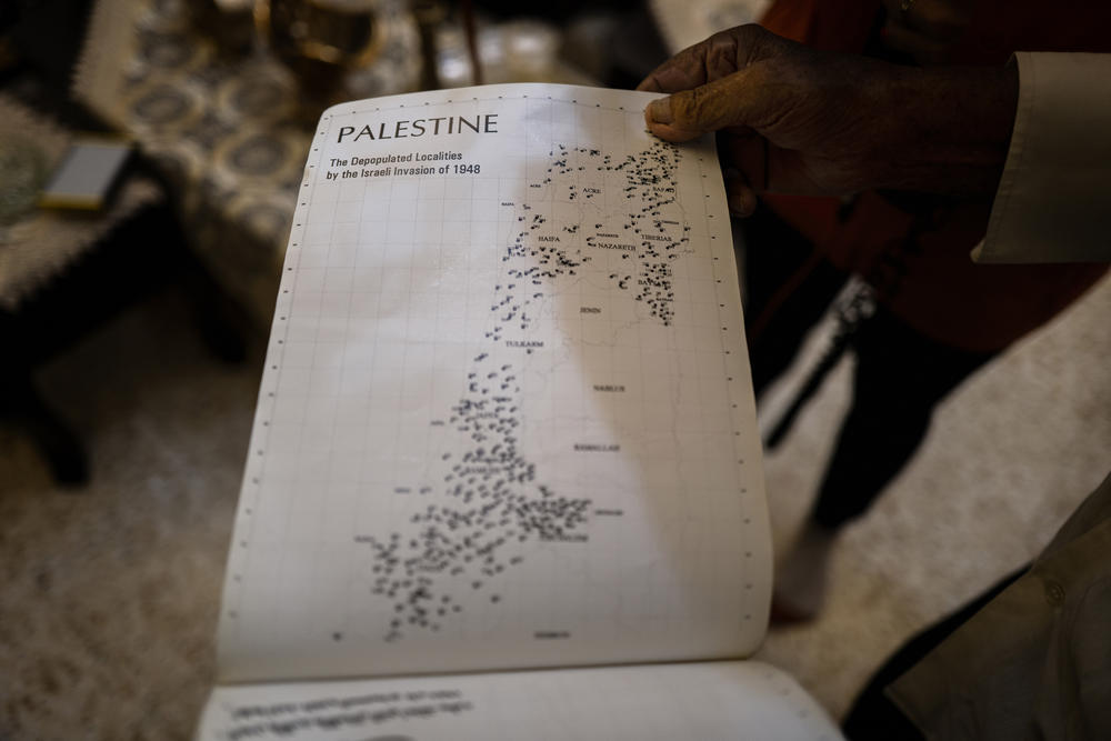 84-year-old Mohammed Suleiman Khader looks through an atlas of old Arab villages — searching for his.