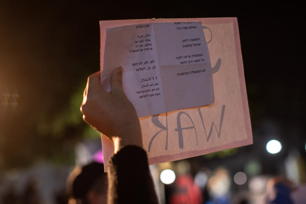 A woman holds a list of chants written in Hebrew and Arabic during the rally.