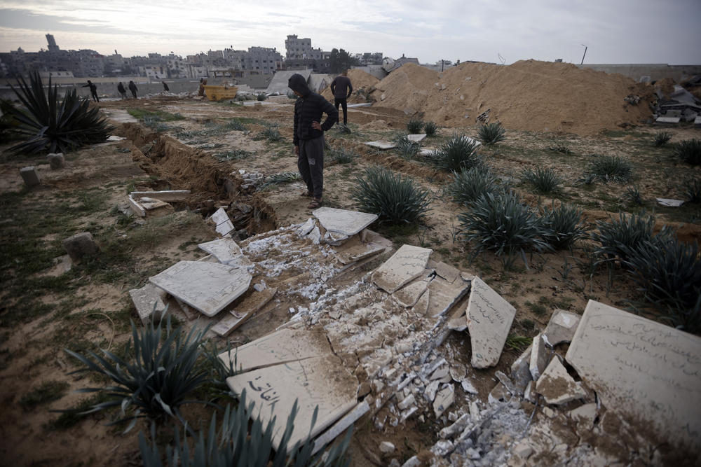 Palestinians inspect damaged graves following an Israeli tank's raid over a cemetery in the Khan Younis refugee camp in southern Gaza on Jan. 17.