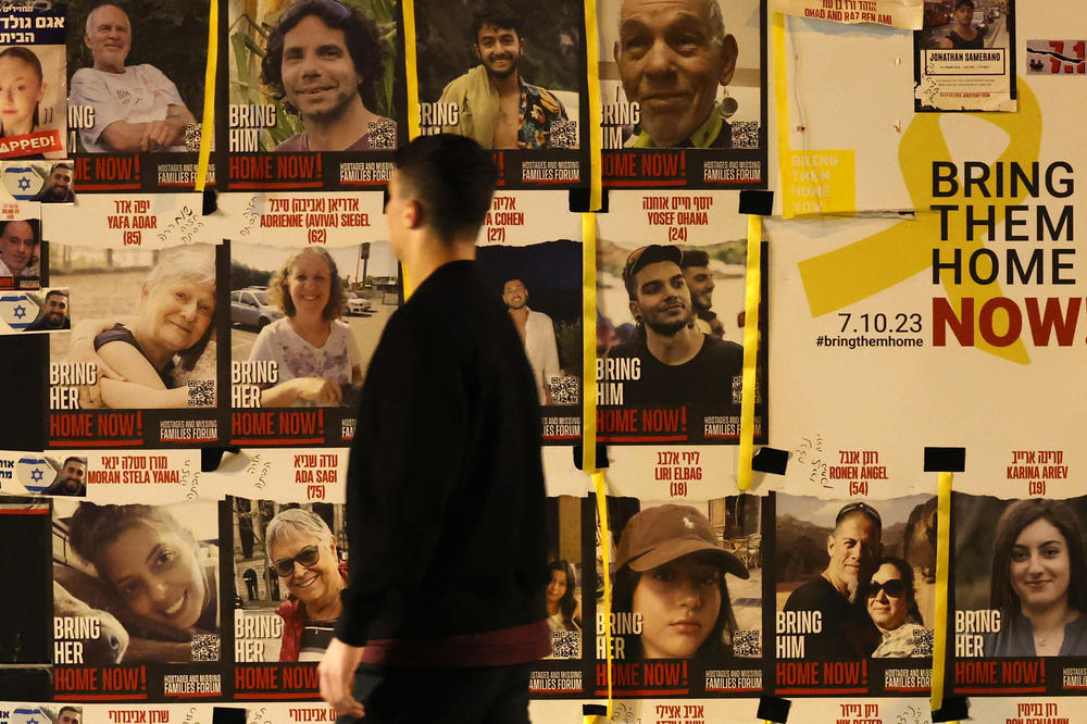 An Israeli youth walks past a wall bearing portraits of Israeli hostages held in Gaza since the Oct. 7 attacks by Hamas in southern Israel, on the sidelines of a rally calling for their release, in Tel Aviv on Jan. 20.