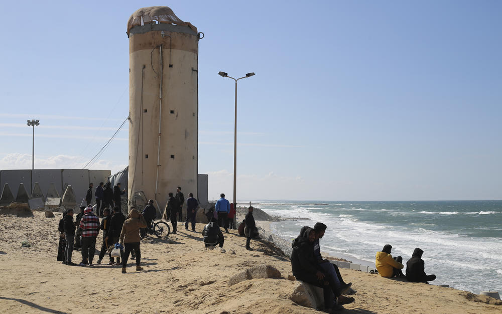 Palestinians displaced by the war in Gaza sit at the southern end of the territory along the coast of the Mediterranean Sea. The barrier in the background is the border between Gaza and Egypt. The fighting has pushed most of Gaza's population into the southern part of the territory.