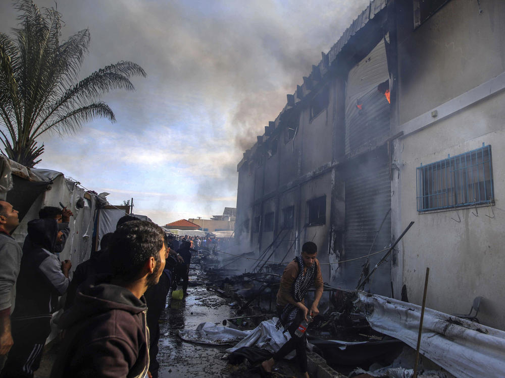Palestinians try to extinguish a fire at a building of an UNRWA vocational training center that displaced people use as a shelter on Jan. 24, 2024.