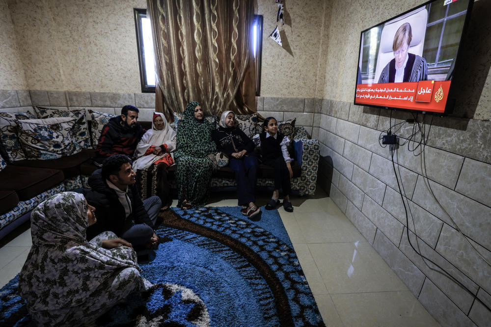 A Palestinian family in Rafah watches the U.N.'s top court on TV on announce its initial decision Friday, Jan. 26, in a case accusing Israel of genocide.