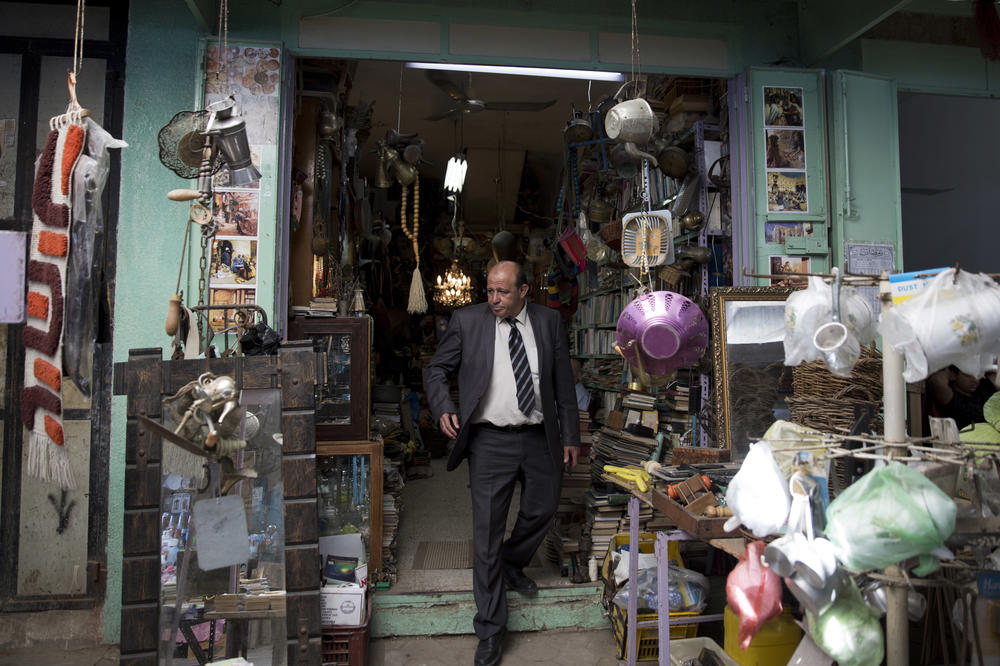 Ayman Hassouna, who taught archaeology in Gaza, walks out of an antiques shop in the middle of the main market in Gaza's Old City, in 2019.