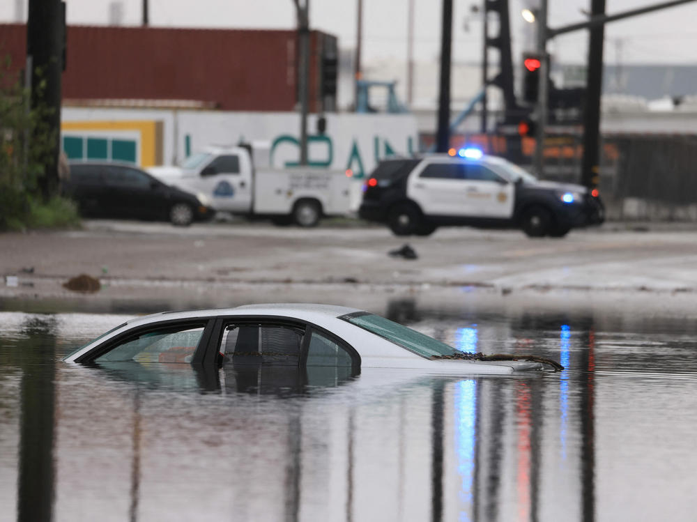A car sits partially submerged on a flooded road during a rain storm in Long Beach, Calif., on Thursday.