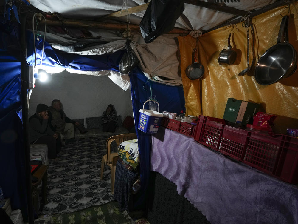 Earthquake survivor Rafet Donmez (center) sits on mattresses with his wife and son inside a tent in Antakya, southern Turkey, on Jan. 12.