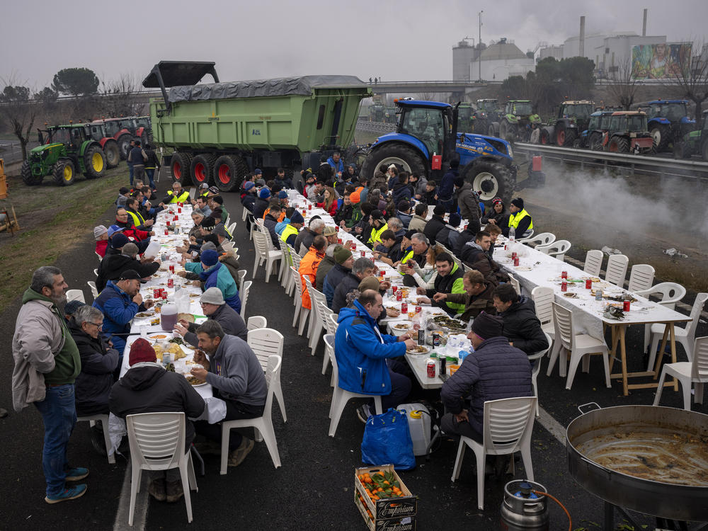 Farmers sit together having lunch after blocking a highway during a protest near Mollerussa, northeast Spain, Tuesday, Feb. 6, 2024.
