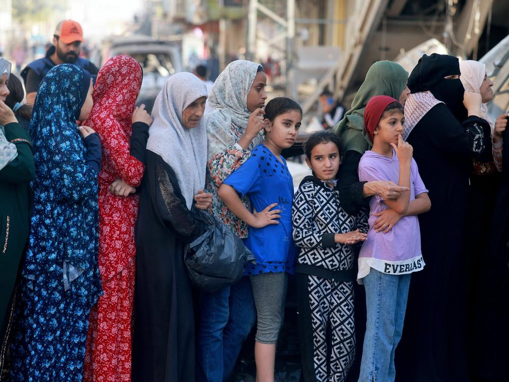 Palestinian women line up to buy fresh bread next to destroyed buildings at the Nuseirat refugee camp in the central Gaza Strip on Nov. 4, 2023.