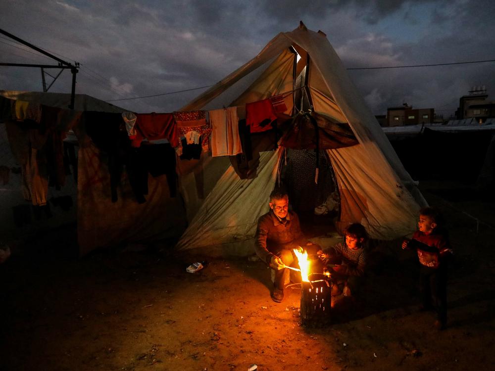 Displaced Palestinians keep warm by a fire near their tent in Rafah, Gaza, on Jan. 23.