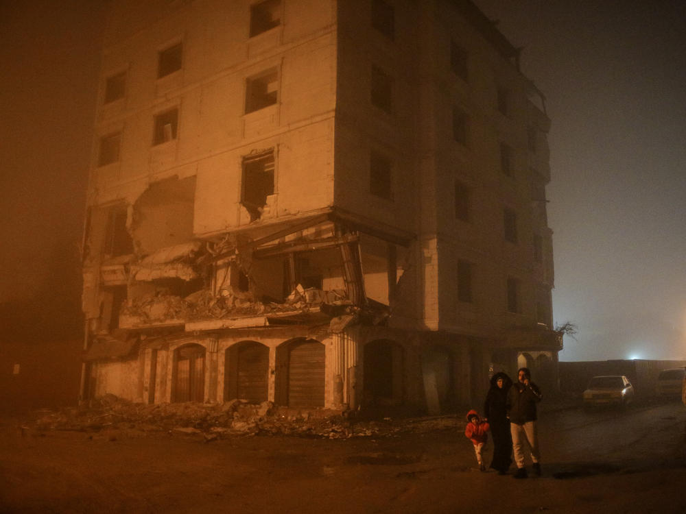 Residents walk by an earthquake-damaged building in Hatay on Monday.