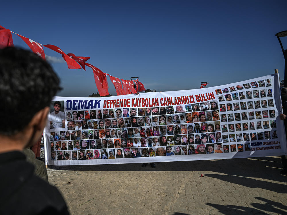 Relatives of missing people hold a banner with portraits and reading 