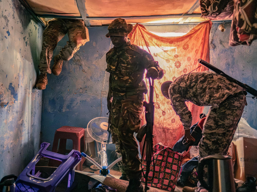 A soldier searches inside the roof cavity of the home of a suspected kush dealer in Waterloo, Sierra Leone. The officers say they discovered large quantities of kush in the house and made several arrests.